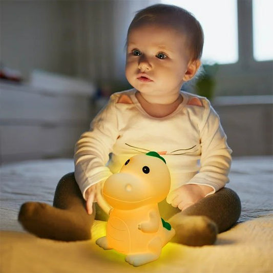 Bébé tenant entre ses mains sa veilleuse bébé dino doucesouge